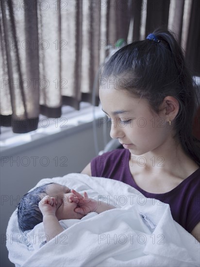 Close up of girl holding newborn baby brother