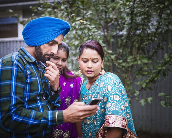 Family in traditional Indian clothing using cell phone