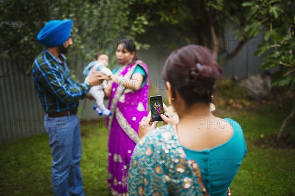 Woman photographing family with cell phone