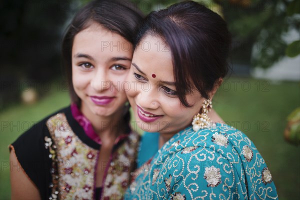 Mother and daughter in Indian clothing hugging outdoors