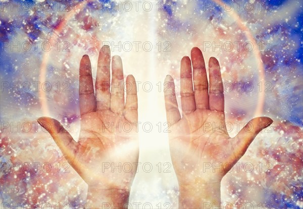 Close up of light glowing from hands of mixed race woman