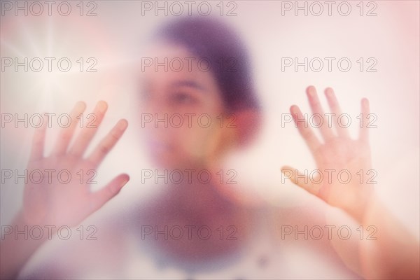 Mixed race girl standing behind frosted glass