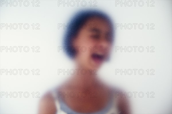 Mixed race girl shouting behind frosted glass