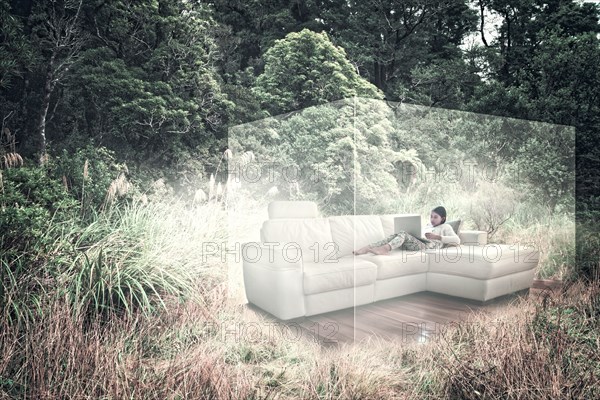 Mixed Race girl using laptop on sofa in virtual cube