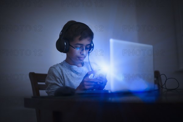 Mixed Race boy using cell phone and laptop