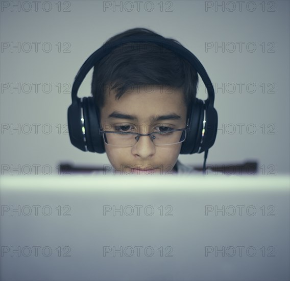 Mixed Race boy listening to laptop with headphones