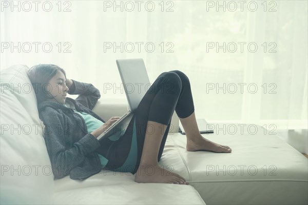 Mixed Race girl using laptop on sofa