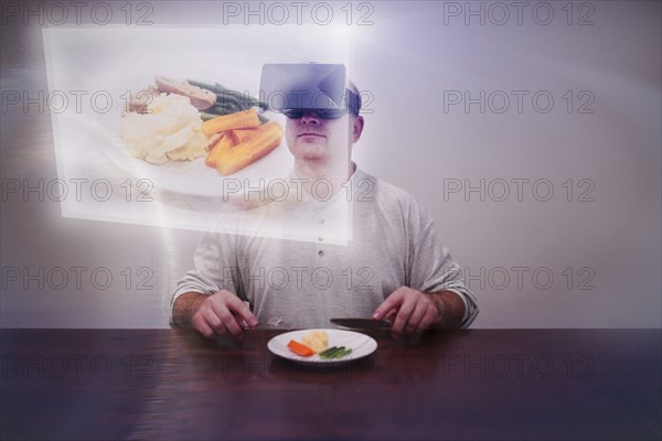 Caucasian man imagining larger meal with VR goggles