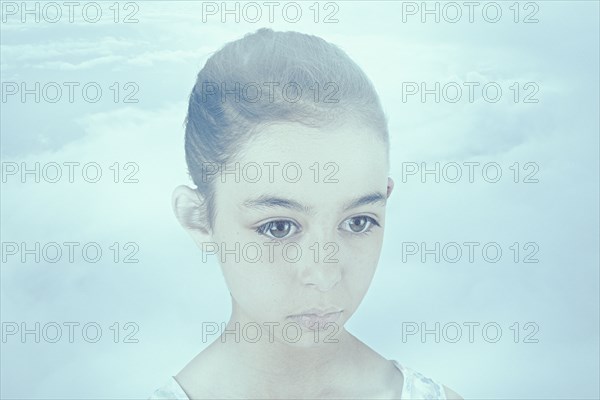 Face of wide-eyed Mixed Race girl in clouds