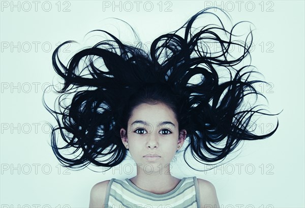 Hair of wide-eyed Mixed Race girl blowing