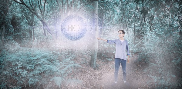 Mixed Race boy with floating sphere in forest