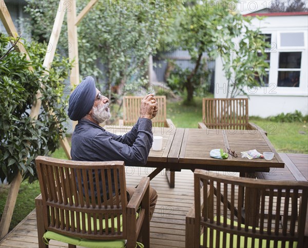 Indian man photographing with cell phone on backyard patio