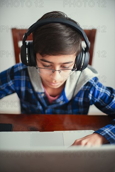 Mixed Race boy listening to laptop with headphones