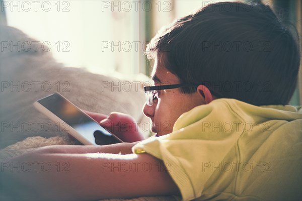 Mixed Race boy texting on cell phone near window