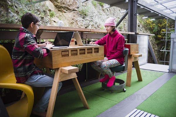 Mixed Race brother and sister using laptops on veranda