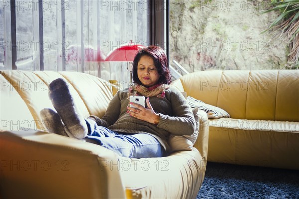 Woman sitting on sofa texting on cell phone