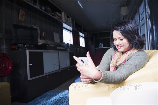 Woman sitting on sofa texting on cell phone