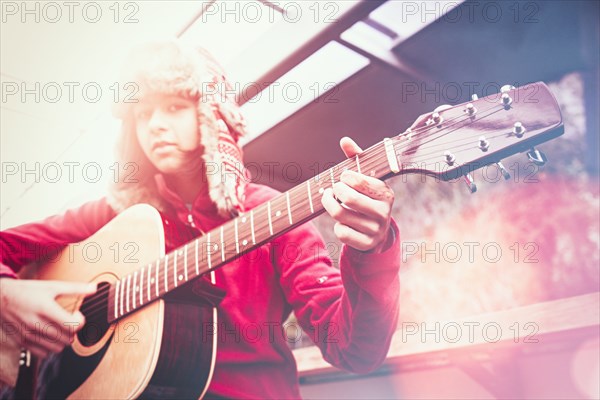 Mixed Race girl playing acoustic guitar