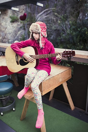 Mixed Race girl playing acoustic guitar on veranda