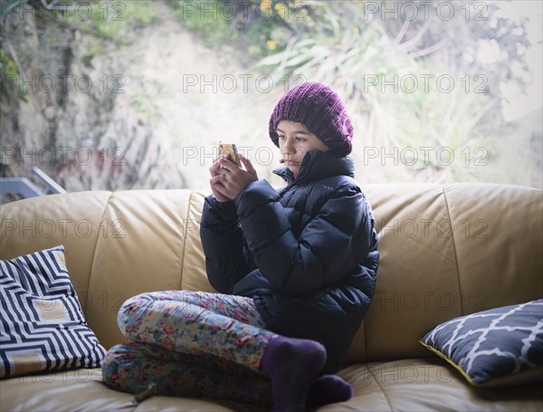 Mixed Race girl sitting on sofa texting on cell phone