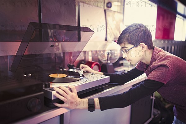 Mixed Race boy playing vinyl record on turntable