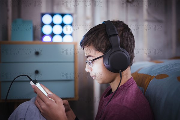 Mixed Race boy listening to cell phone with headphones