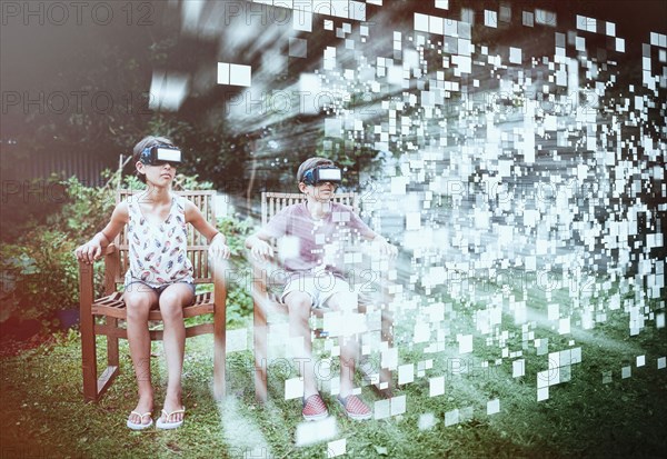 Mixed Race brother and sister viewing hovering pixels with vr goggles