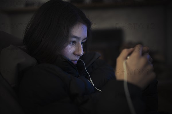 Mixed Race girl listening to cell phone with earbuds