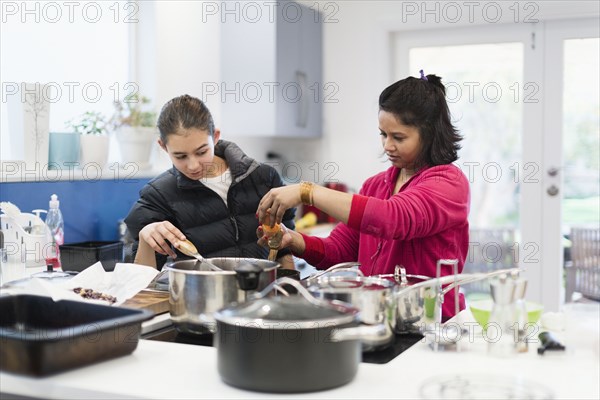 Mother and daughter looking down at cooking food