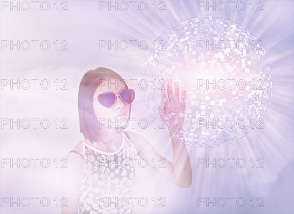 Mixed Race girl wearing sunglasses touching hovering pixel sphere