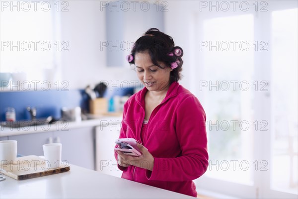 Indian woman wearing hair curlers texting on cell phone