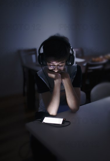 Mixed Race boy listening to cell phone with headphones