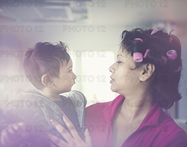 Indian mother wearing curlers holding son