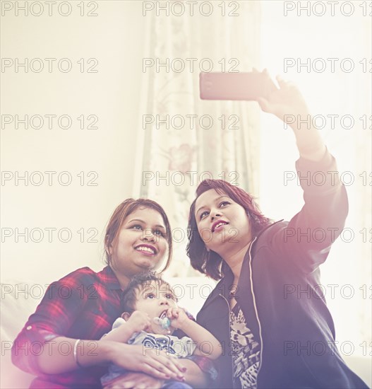 Indian women posing for cell phone selfie with baby boy