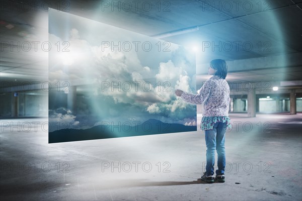 Mixed Race girl watching clouds on virtual screen in parking garage