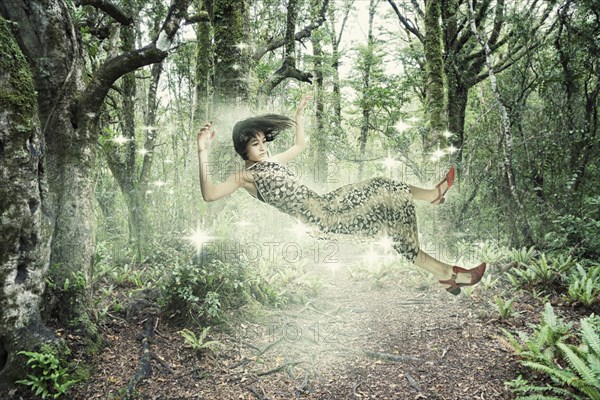 Mixed Race girl floating in forest