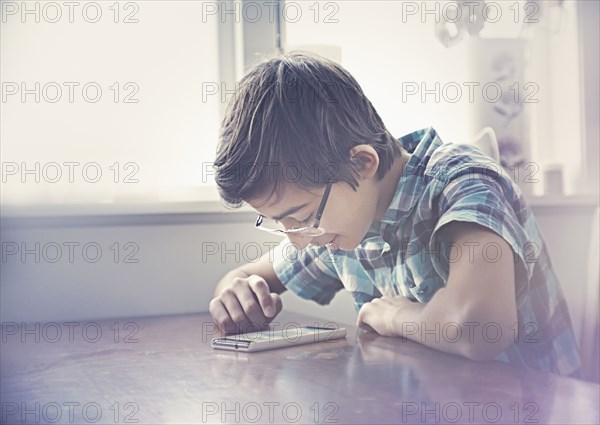 Smiling Mixed Race boy texting on cell phone