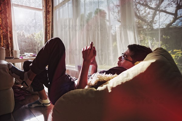 Mixed Race boy texting on cell phone near window