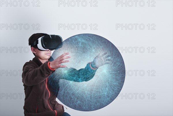 Mixed Race boy wearing VR goggles holding sphere