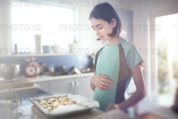 Mixed Race girl looking at tray of cookies
