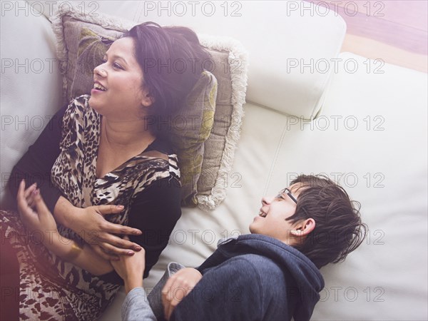 Mother and son laying on sofa and laughing