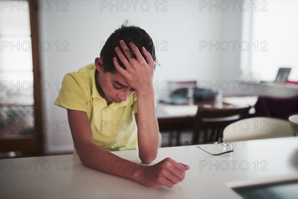 Crying Mixed Race boy with hand on head