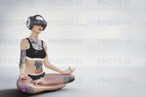 Woman with tattoos meditating and wearing virtual reality helmet