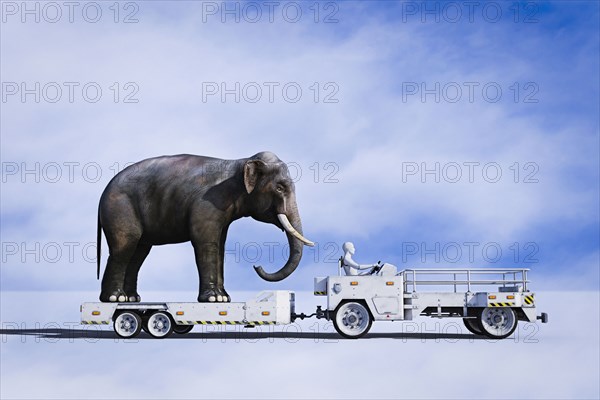 Robot driving tractor pulling elephant on trailer