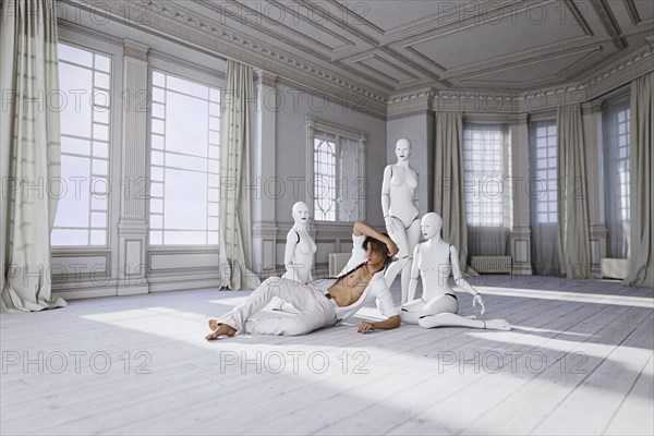 Man sitting on floor with women robots