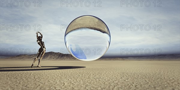 Futuristic woman watching floating sphere in desert