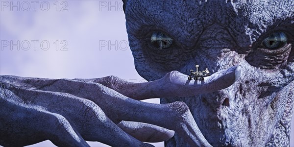 Alien examining tiny vehicle on finger