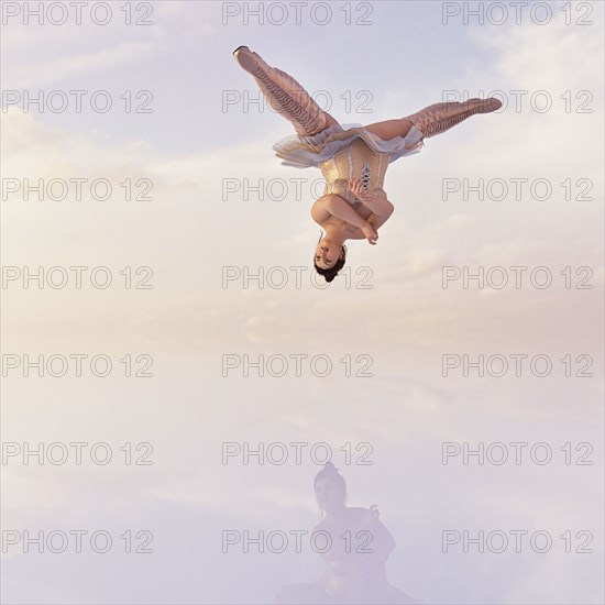 Woman wearing corset and boots upside-down in clouds