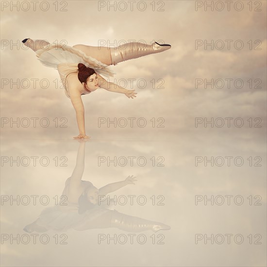 Woman wearing corset and boots balancing on hand in clouds