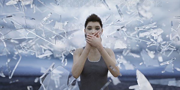 Shards of glass surrounding woman covering mouth with hands